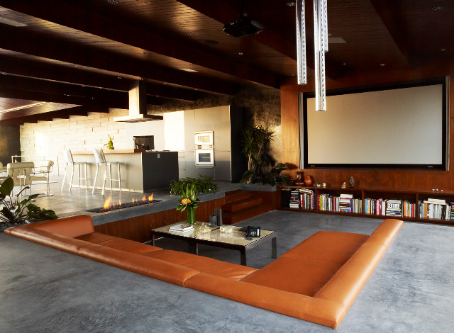 This is an example of a large modern open plan home cinema in Los Angeles with a projector screen and grey floors.
