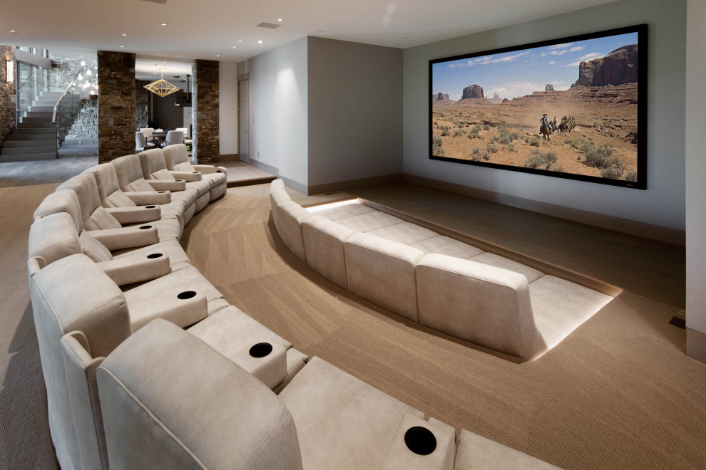 Idée de décoration pour une salle de cinéma chalet ouverte avec un mur gris, moquette, un écran de projection et un sol beige.