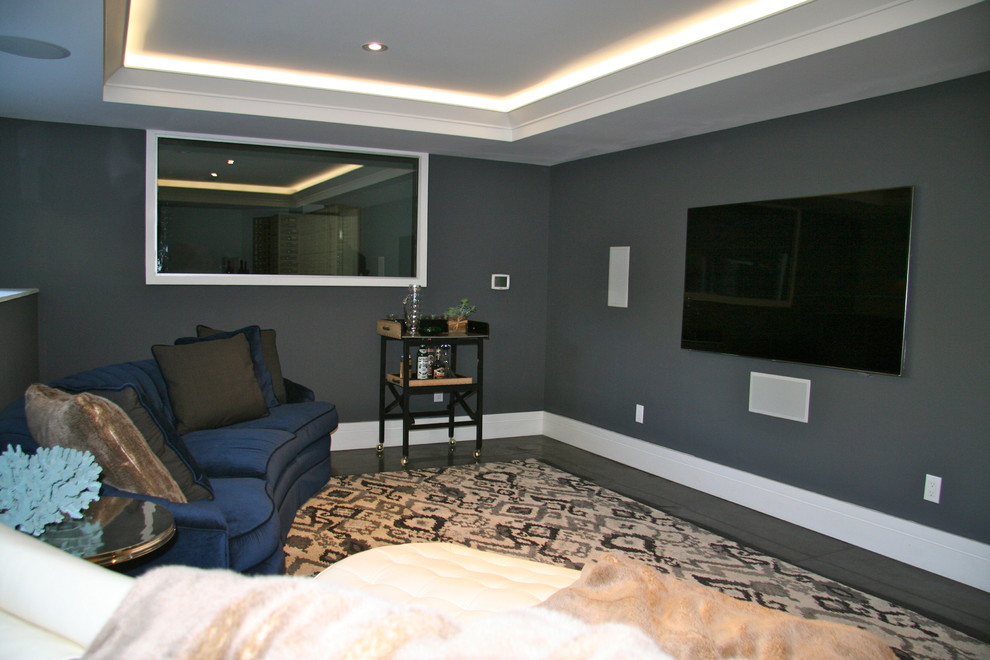 Modelo de cine en casa cerrado minimalista de tamaño medio con paredes grises, suelo de cemento y televisor colgado en la pared