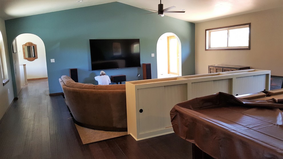 Modern inredning av ett stort öppen hemmabio, med grå väggar, mörkt trägolv och en väggmonterad TV
