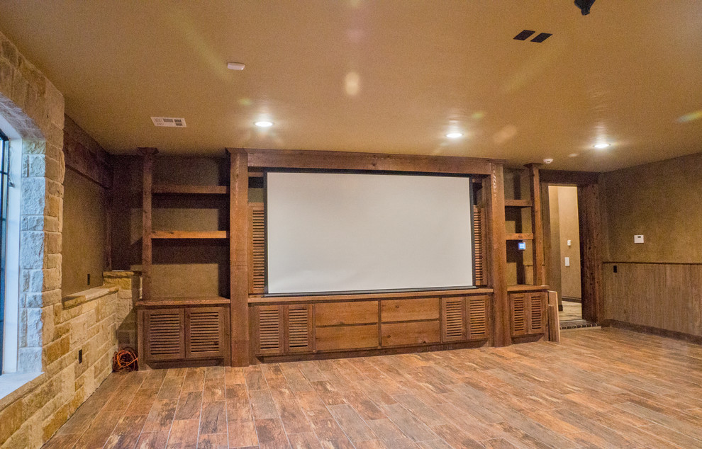 Foto de cine en casa abierto clásico grande con paredes marrones, suelo de madera en tonos medios y pared multimedia