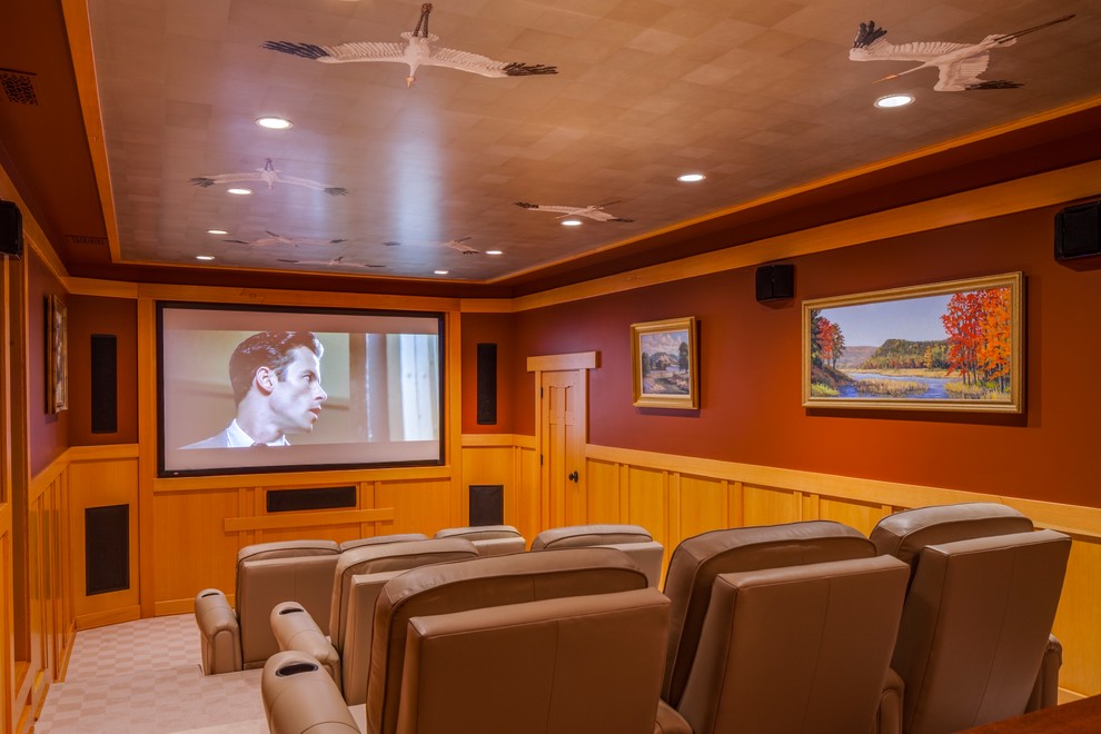 This is an example of a medium sized traditional enclosed home cinema in Portland Maine with red walls, carpet, a projector screen and beige floors.