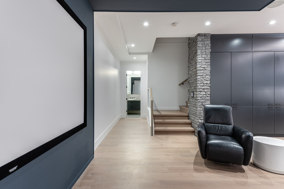 Ejemplo de cine en casa abierto actual grande con paredes blancas, suelo de madera clara, pantalla de proyección y suelo beige