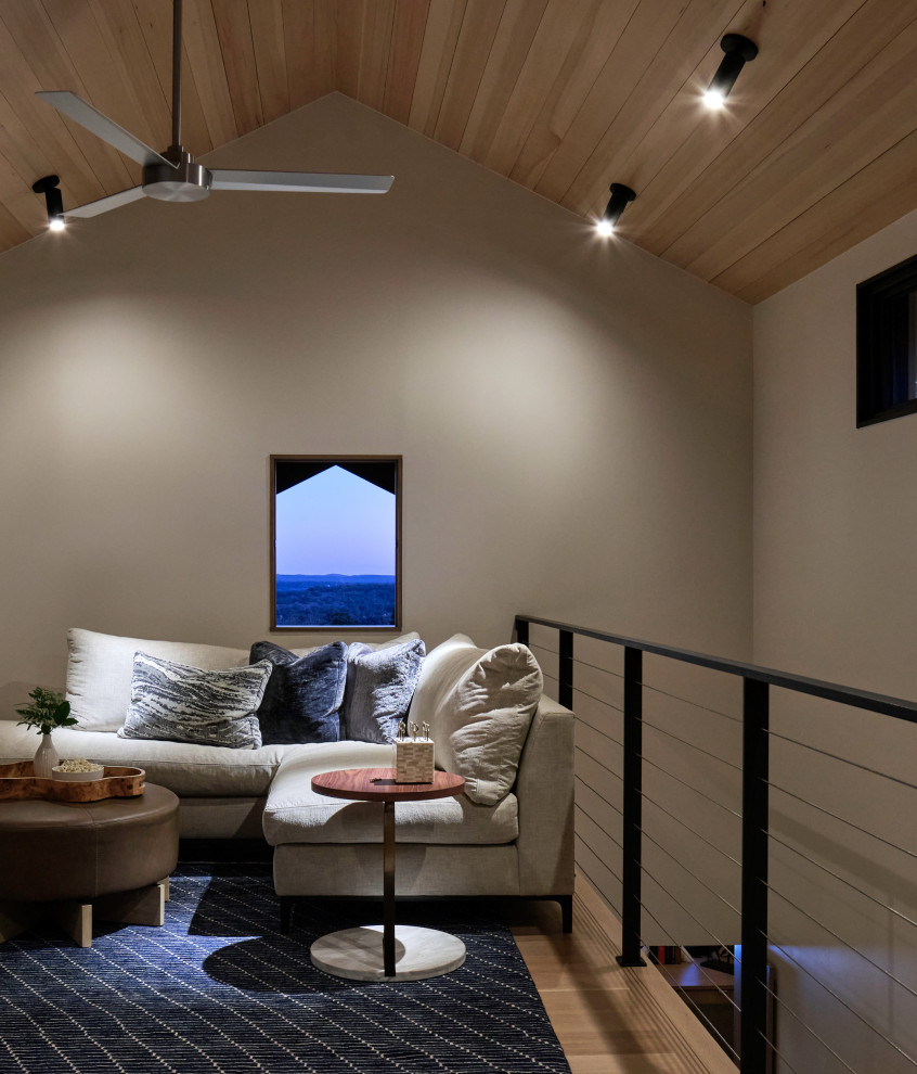 Imagen de cine en casa abierto actual pequeño con paredes blancas, suelo de madera clara y televisor colgado en la pared