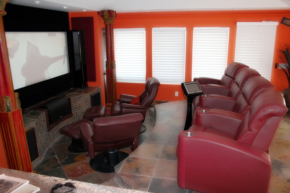 Cette image montre une salle de cinéma traditionnelle fermée avec un mur orange, tomettes au sol, un écran de projection et un sol multicolore.