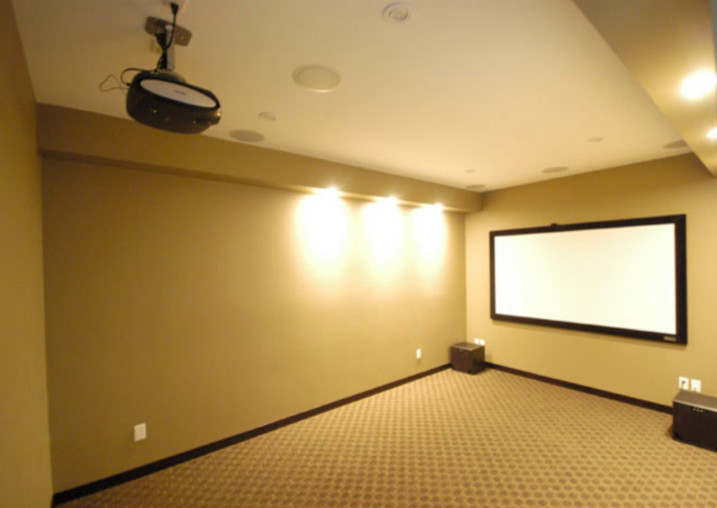 Large classic enclosed home cinema in Orange County with beige walls, carpet, brown floors and a projector screen.