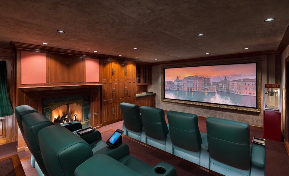 Cette image montre une grande salle de cinéma traditionnelle fermée avec un mur rose, moquette, un écran de projection et un sol rose.