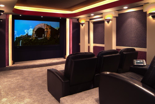 Home theater - mid-sized traditional enclosed carpeted home theater idea in Other with multicolored walls and a wall-mounted tv
