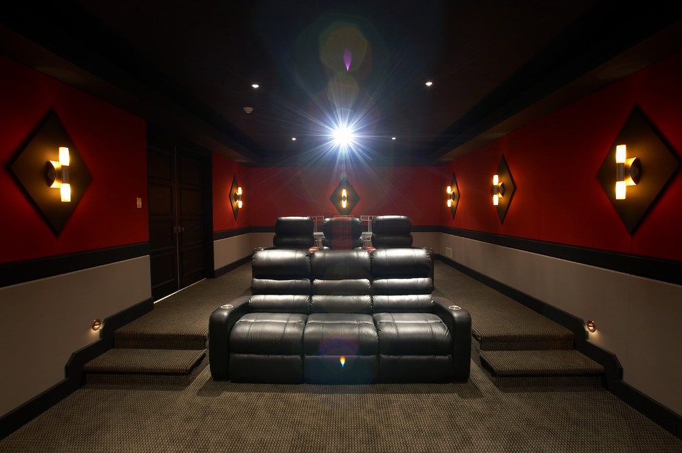 Cette image montre une salle de cinéma traditionnelle fermée et de taille moyenne avec moquette, un écran de projection et un mur rouge.