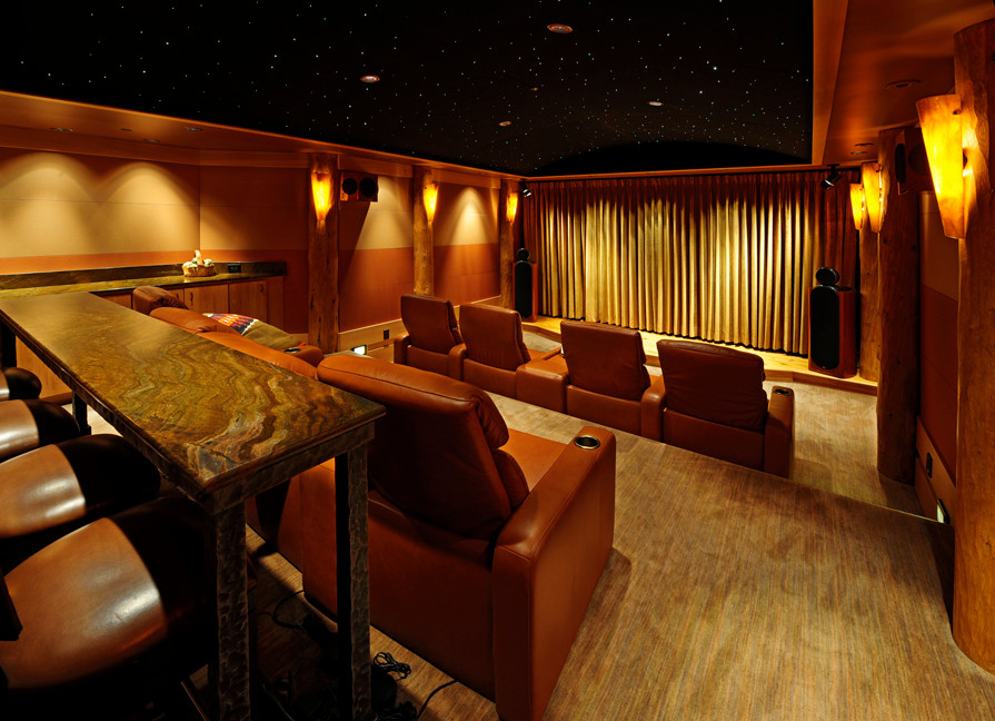 Cette photo montre une grande salle de cinéma chic fermée avec un mur beige, un sol en bois brun et un sol marron.
