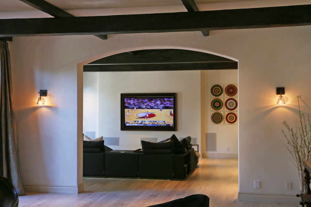 Ejemplo de cine en casa abierto actual grande con paredes blancas, suelo de madera clara y televisor colgado en la pared