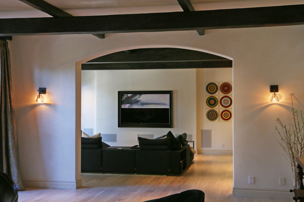 Foto på ett stort funkis öppen hemmabio, med vita väggar, ljust trägolv och en väggmonterad TV