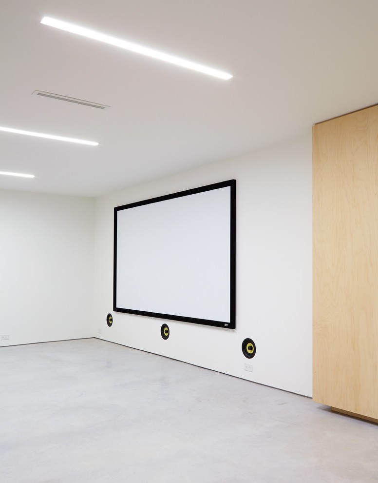 Bild på ett mellanstort funkis öppen hemmabio, med vita väggar, betonggolv och projektorduk