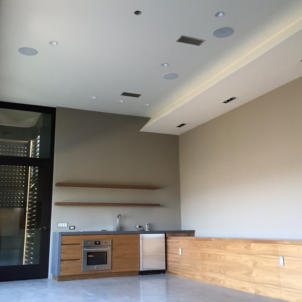 This is an example of a medium sized modern enclosed home cinema in Orange County with grey walls, concrete flooring, a wall mounted tv and grey floors.