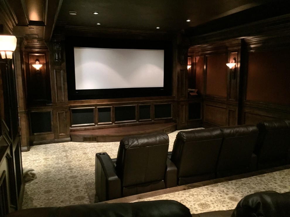 Cette image montre une grande salle de cinéma traditionnelle fermée avec un mur beige, un sol en carrelage de céramique et un téléviseur encastré.