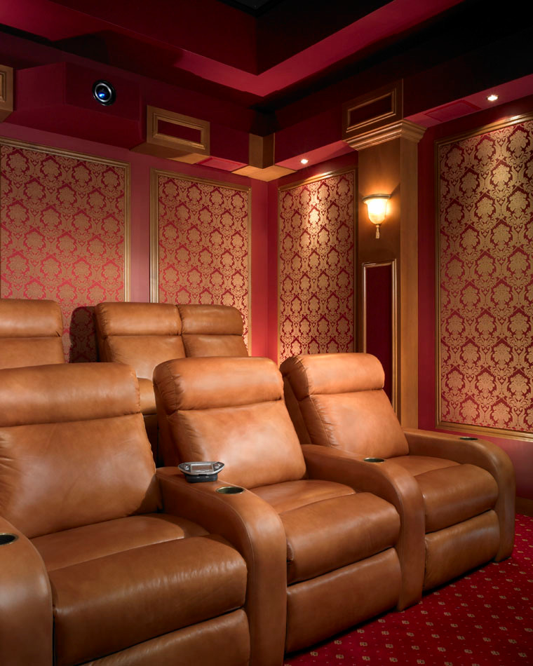 Cette image montre une salle de cinéma traditionnelle de taille moyenne et fermée avec un mur rouge, moquette et un écran de projection.