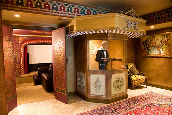 На фото: огромный изолированный домашний кинотеатр в средиземноморском стиле с красными стенами, полом из известняка и проектором с
