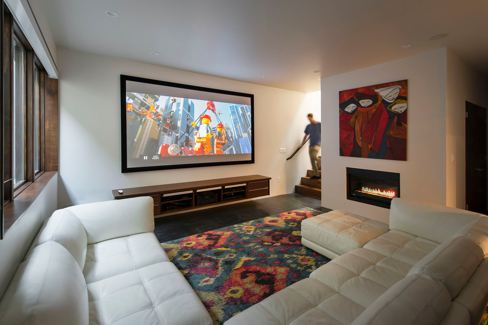 Ejemplo de cine en casa abierto minimalista de tamaño medio con paredes blancas, suelo de cemento y pantalla de proyección