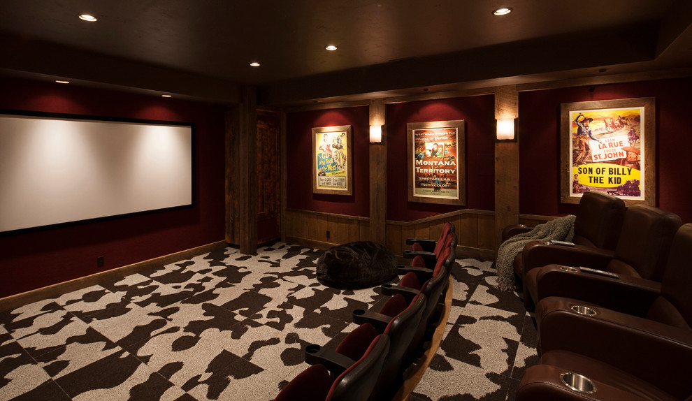 Exemple d'une grande salle de cinéma montagne fermée avec un mur rouge, moquette, un téléviseur fixé au mur et un sol multicolore.