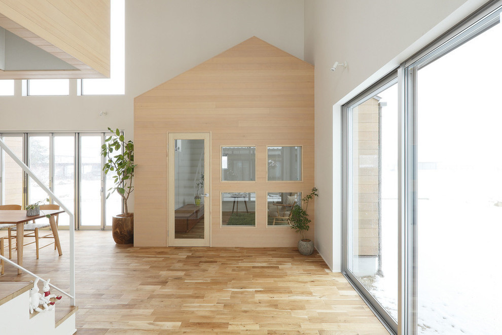 Ejemplo de cine en casa abierto contemporáneo de tamaño medio con paredes blancas, suelo de madera clara, televisor colgado en la pared y suelo beige