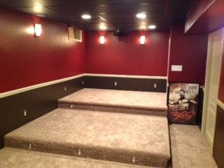 Cette photo montre une petite salle de cinéma fermée avec un mur rouge, moquette, un téléviseur encastré et un sol beige.