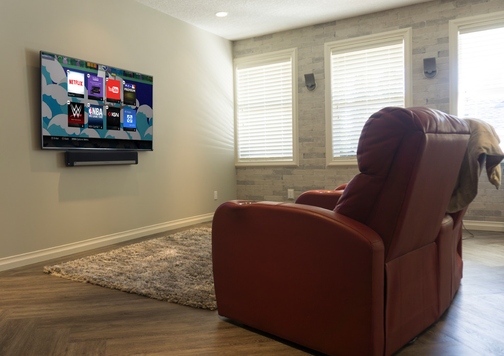 Imagen de cine en casa abierto tradicional renovado de tamaño medio con paredes beige, suelo de madera en tonos medios, televisor colgado en la pared y suelo marrón