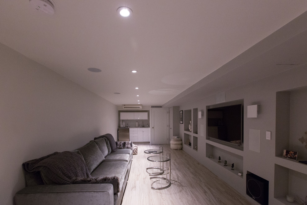 Ejemplo de cine en casa abierto moderno grande con paredes grises, suelo de bambú y televisor colgado en la pared