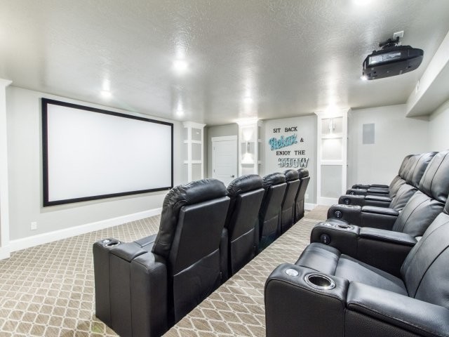 Пример оригинального дизайна: большой изолированный домашний кинотеатр в стиле неоклассика (современная классика) с серыми стенами, ковровым покрытием и проектором