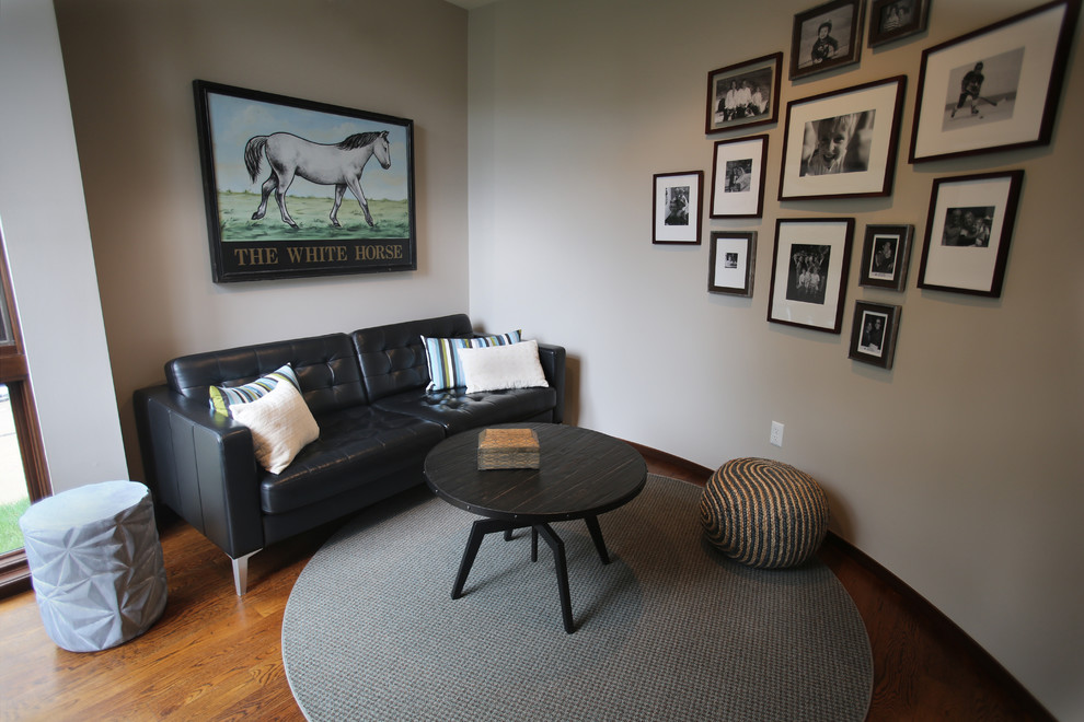 Diseño de cine en casa cerrado bohemio pequeño con paredes grises, suelo de madera en tonos medios, televisor colgado en la pared y suelo marrón