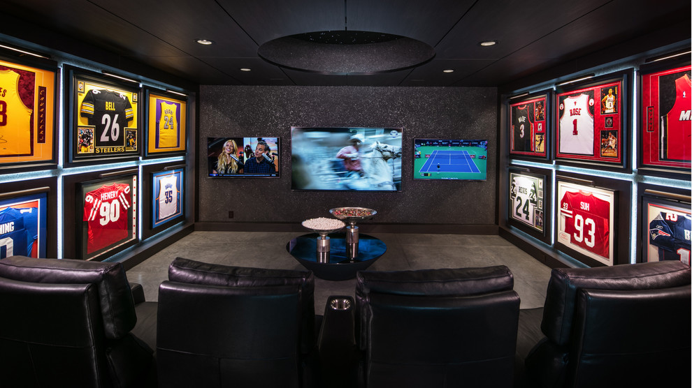 Example of a large trendy enclosed concrete floor and gray floor home theater design in Omaha with black walls and a wall-mounted tv