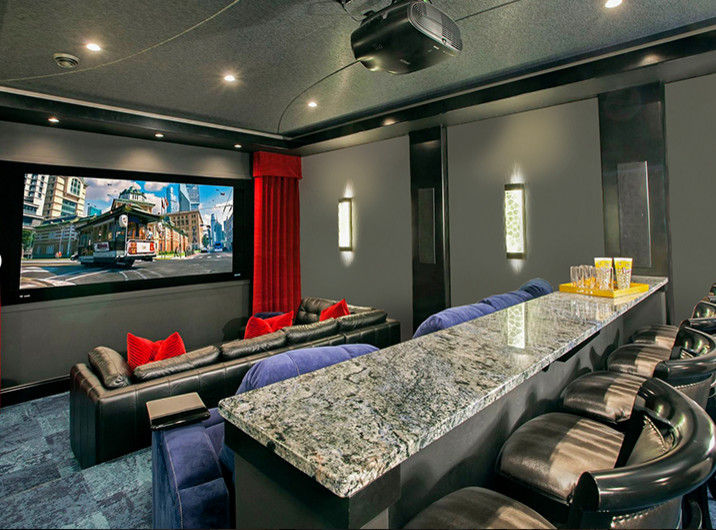 На фото: большой изолированный домашний кинотеатр с ковровым покрытием, проектором и зеленым полом с