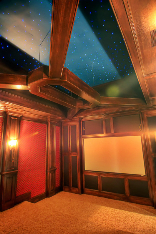 Home theater - large traditional enclosed carpeted home theater idea in Charlotte with black walls and a media wall