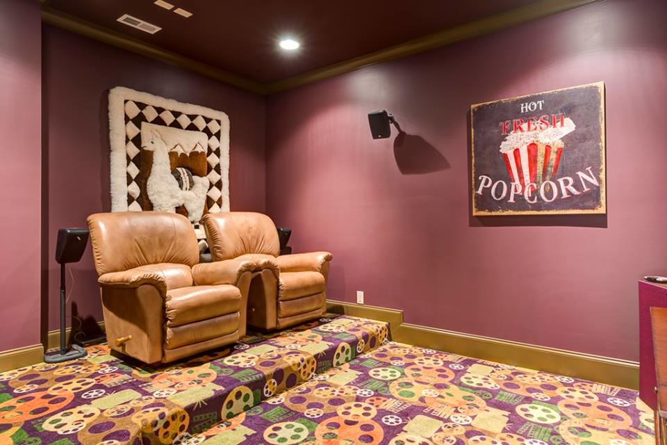 Стильный дизайн: изолированный домашний кинотеатр среднего размера в стиле рустика с ковровым покрытием, фиолетовыми стенами, телевизором на стене и разноцветным полом - последний тренд
