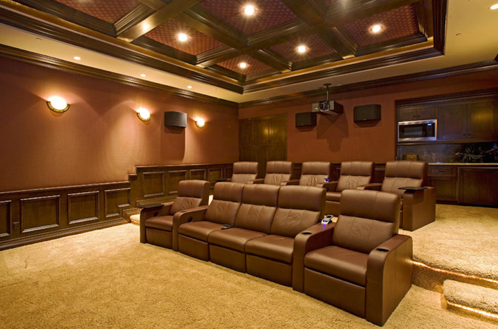Пример оригинального дизайна: большой изолированный домашний кинотеатр с оранжевыми стенами, ковровым покрытием и проектором