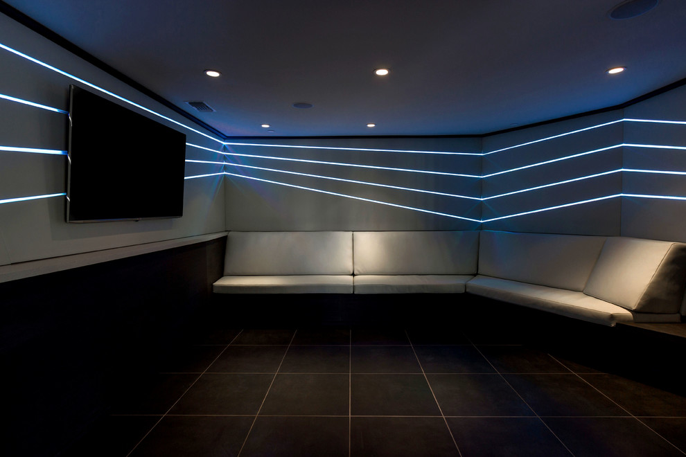 Cette image montre une petite salle de cinéma design fermée avec un sol en marbre, un mur gris, un téléviseur fixé au mur et un sol noir.