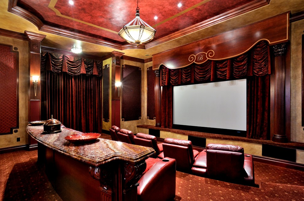 Cette image montre une très grande salle de cinéma traditionnelle fermée avec un mur rouge, moquette, un écran de projection et un sol rouge.