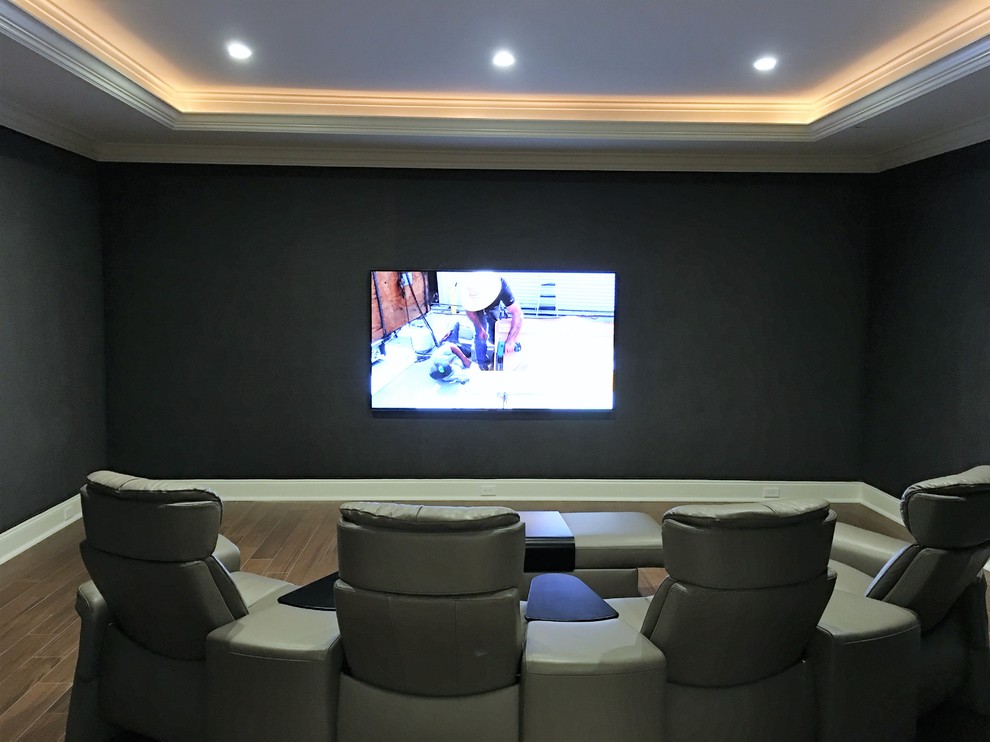 Inspiration for a large classic enclosed home cinema in New York with grey walls, medium hardwood flooring, a wall mounted tv and brown floors.