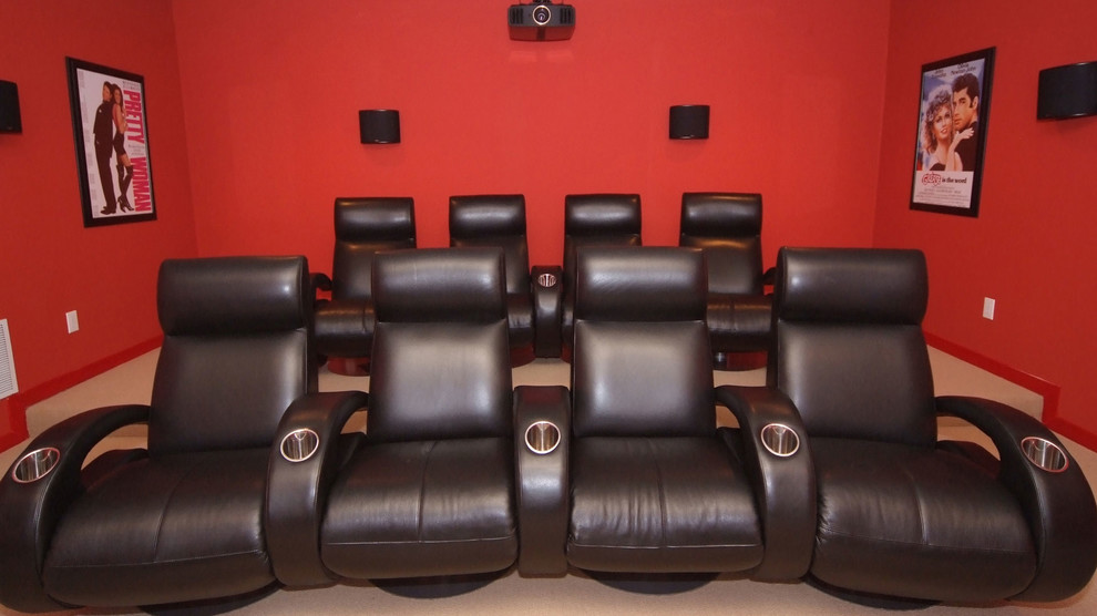 Aménagement d'une grande salle de cinéma moderne fermée avec un mur rouge, moquette et un téléviseur fixé au mur.