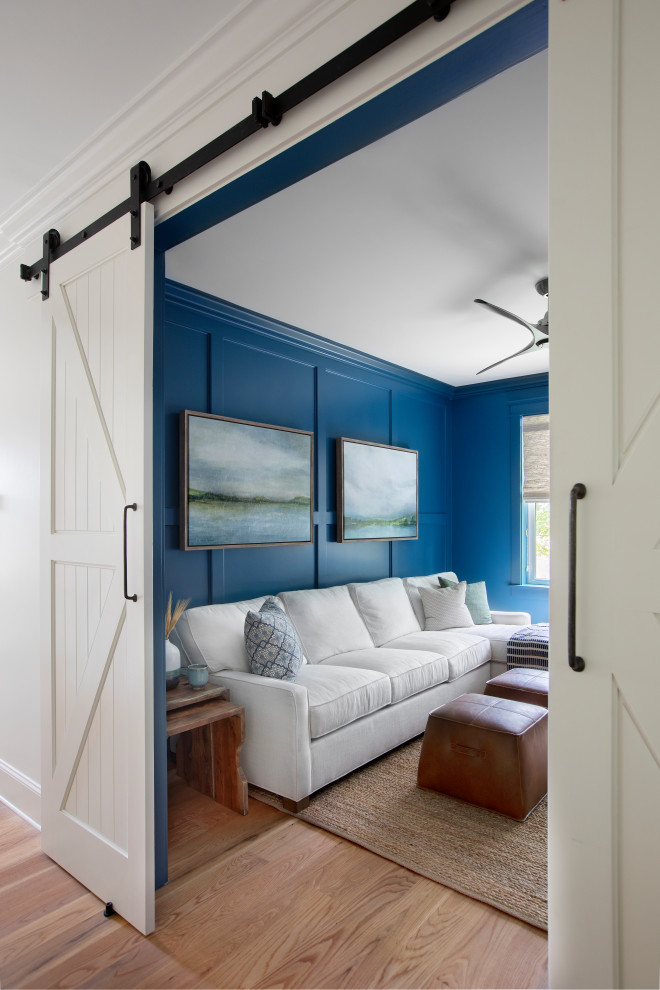 Modelo de cine en casa cerrado marinero con paredes azules, suelo de madera clara y televisor colgado en la pared