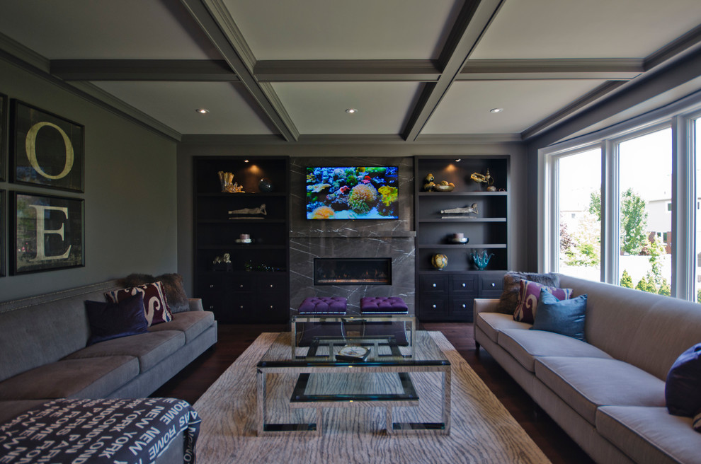 Modelo de cine en casa abierto clásico renovado grande con paredes grises, suelo de madera oscura y televisor colgado en la pared