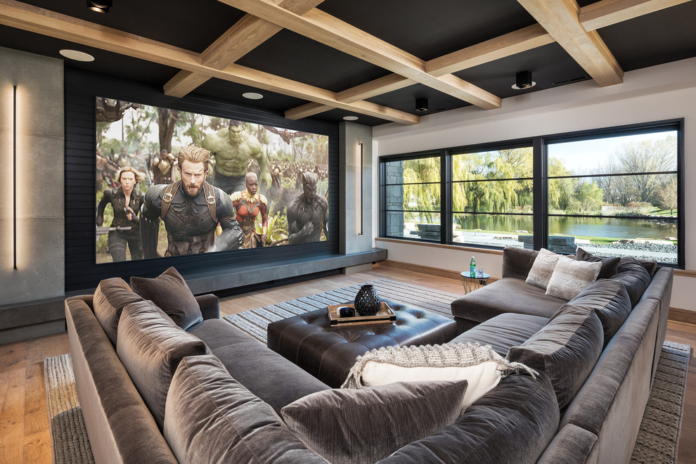 This is an example of a large contemporary open plan home cinema in Other with white walls, medium hardwood flooring, a projector screen and brown floors.