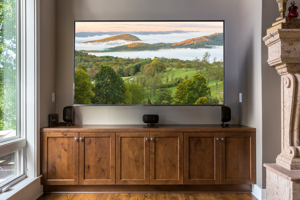 Klassisk inredning av ett mellanstort öppen hemmabio, med grå väggar, mellanmörkt trägolv och en väggmonterad TV