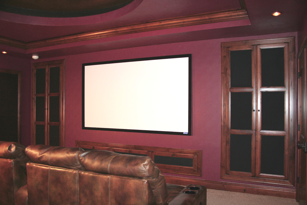Large traditional enclosed home cinema in Denver with red walls, carpet and a projector screen.