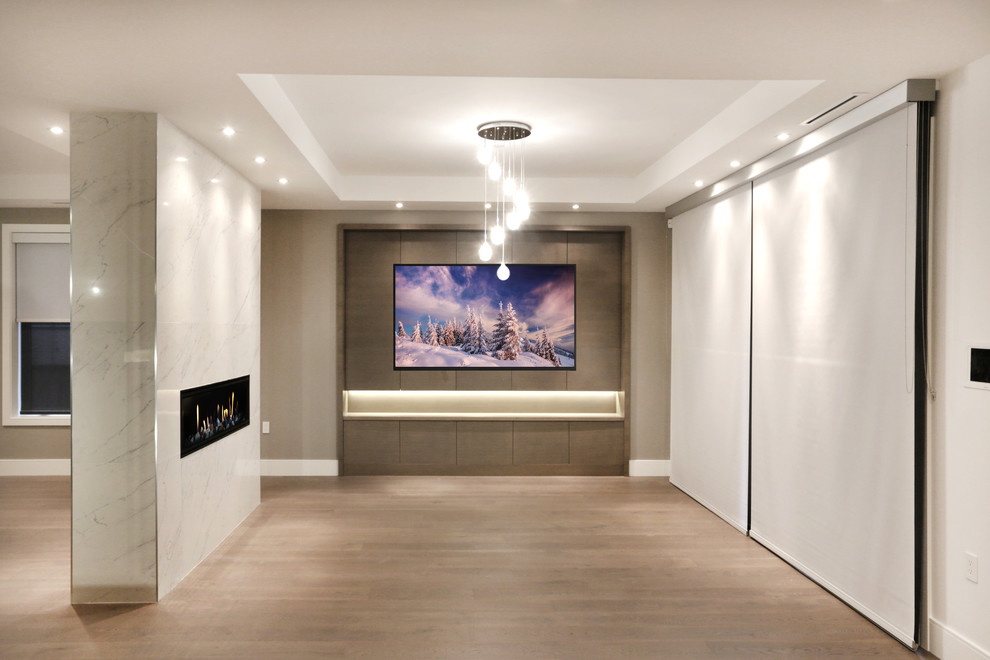 Diseño de cine en casa cerrado actual extra grande con paredes grises, suelo de madera clara, televisor colgado en la pared y suelo beige