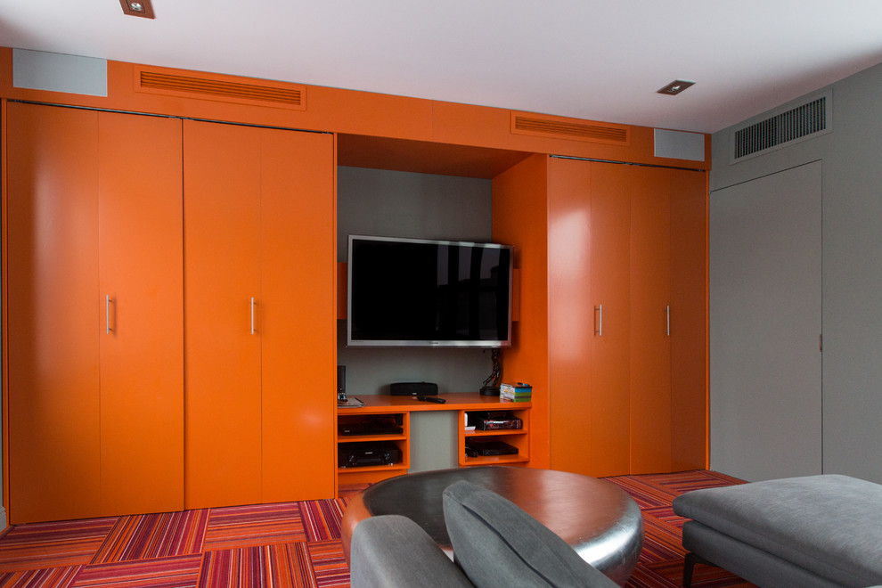 Immagine di un piccolo home theatre moderno chiuso con pareti arancioni, moquette, parete attrezzata e pavimento multicolore