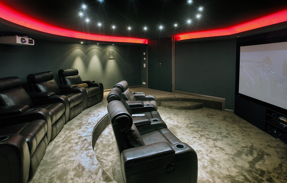 Modelo de cine en casa cerrado moderno de tamaño medio con paredes grises, moqueta y pantalla de proyección