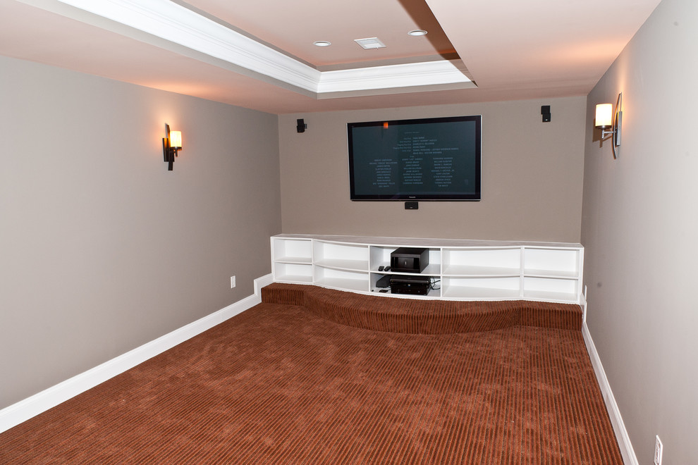 На фото: большой домашний кинотеатр в классическом стиле с ковровым покрытием и телевизором на стене с