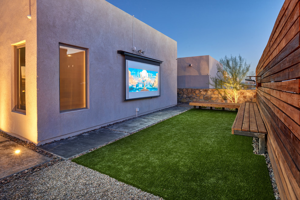 Aménagement d'une petite salle de cinéma contemporaine ouverte avec un mur blanc, sol en béton ciré, un écran de projection et un sol vert.