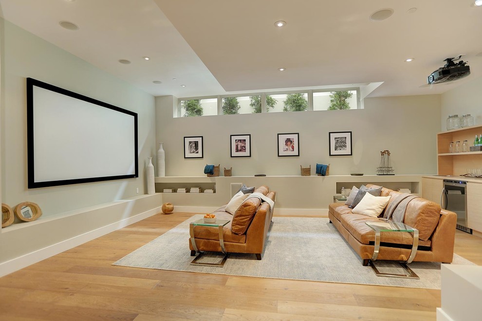 Ejemplo de cine en casa abierto minimalista grande con paredes grises, suelo de madera en tonos medios y pantalla de proyección