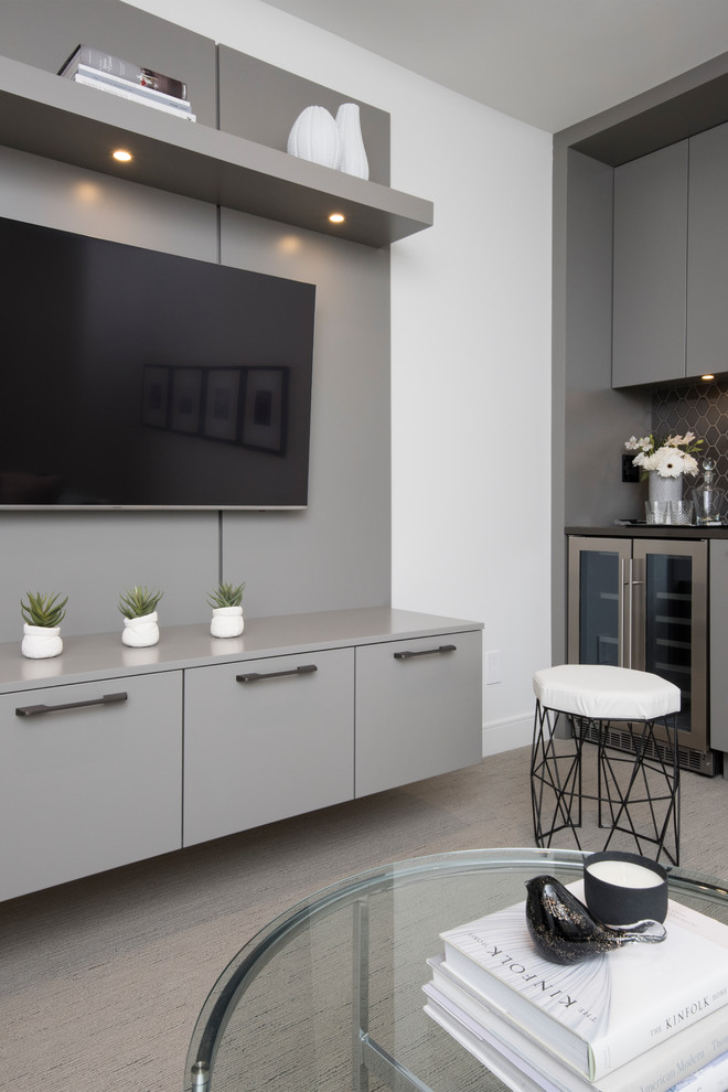 Diseño de cine en casa cerrado moderno de tamaño medio con paredes grises, moqueta, televisor colgado en la pared y suelo gris